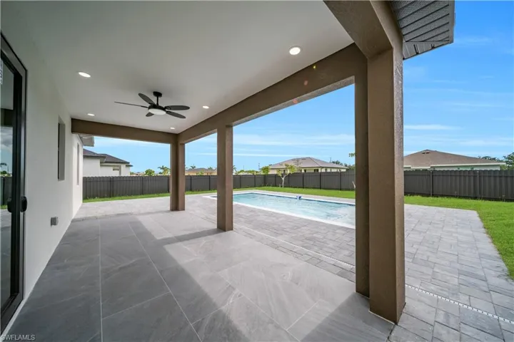 Fenced backyard with ceiling fan and a patio area