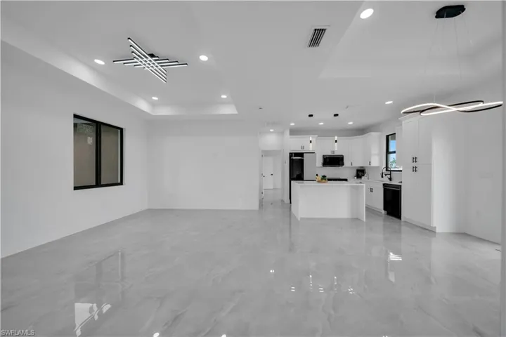 Unfurnished living room featuring a tray ceiling, recessed lighting, and light marble finish floors