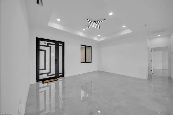 Spare room with marble tiled floors, a tray ceiling, and recessed lighting