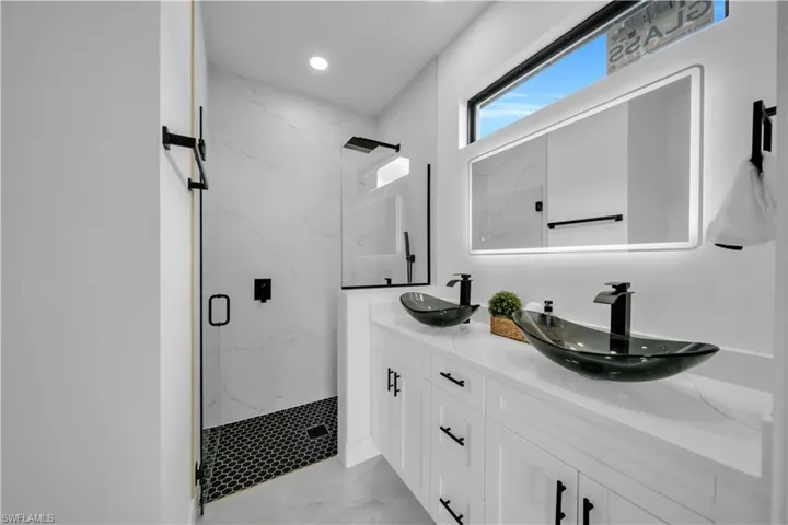 Bathroom with a marble finish shower, double vanity, marble finish floors, and recessed lighting
