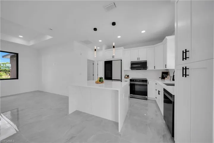 Kitchen featuring black electric range, stainless steel microwave, fridge, a center island, and dishwasher