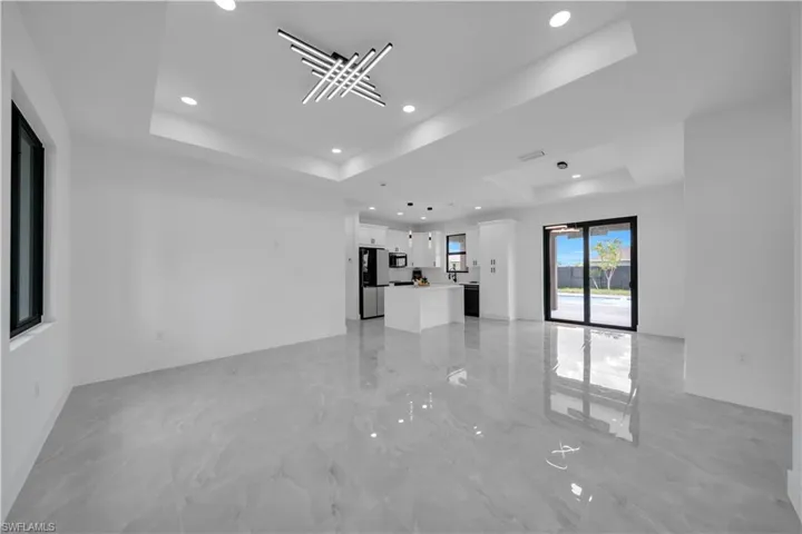 Unfurnished living room with a tray ceiling, recessed lighting, and light marble finish flooring