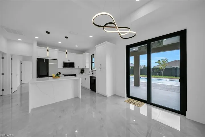 Kitchen with black appliances, white cabinetry, light countertops, decorative light fixtures, and recessed lighting