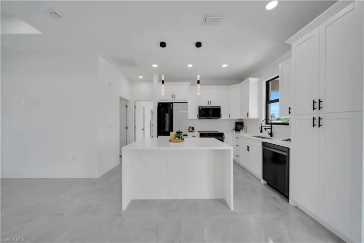 Kitchen featuring black appliances, a kitchen island, white cabinetry, recessed lighting, and decorative light fixtures