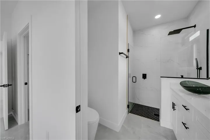 Bathroom featuring a marble finish shower, vanity, marble look tile flooring, and recessed lighting