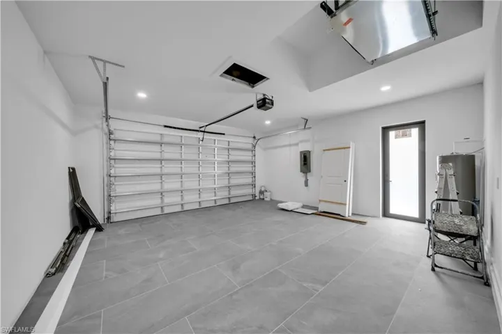 Garage featuring recessed lighting, a garage door opener, electric panel, and water heater