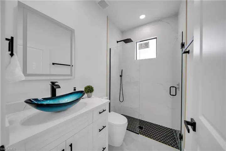 Bathroom with vanity and a marble finish shower