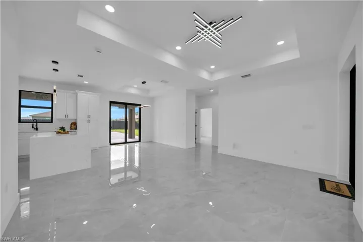 Empty room featuring a tray ceiling, recessed lighting, and light marble finish flooring