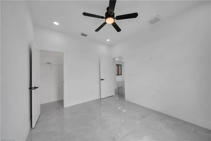 Unfurnished bedroom featuring light marble finish flooring, a spacious closet, recessed lighting, ceiling fan, and a closet