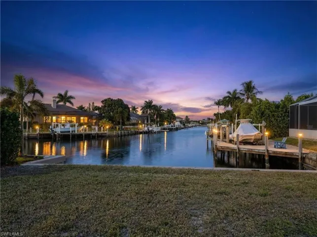 Dock featuring a water view, a lawn, and boat lift