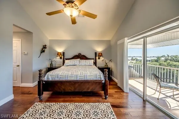 Bedroom with lofted ceiling, access to outside, dark wood-type flooring, and ceiling fan