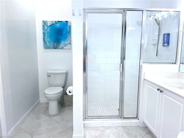 Full bathroom featuring vanity, a shower stall, and light tile patterned flooring