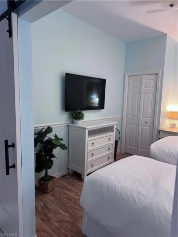 Bedroom featuring dark wood-style floors, a closet, and a barn door