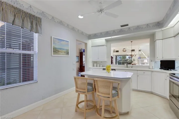 Kitchen with white cabinetry, a center island, a kitchen bar, and light countertops