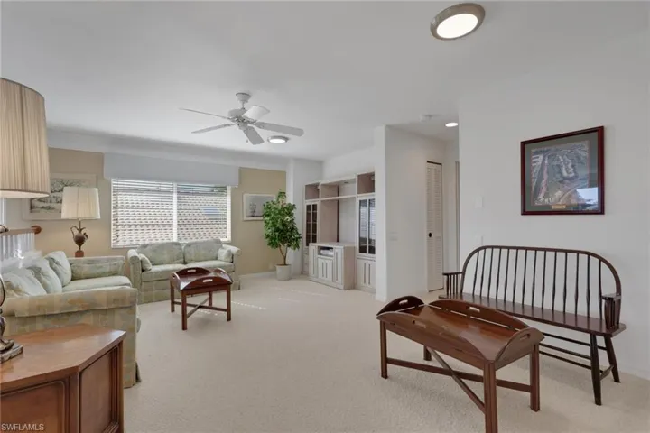 Living area featuring light carpet and a ceiling fan