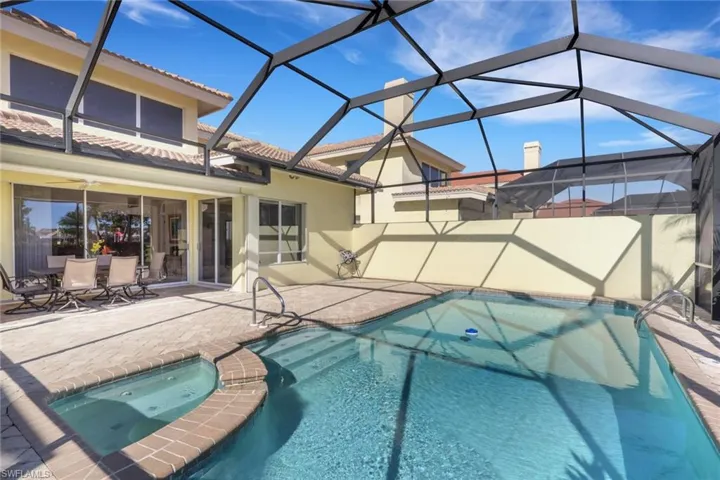 View of pool featuring a sunroom, glass enclosure, a patio area, and a pool with connected hot tub
