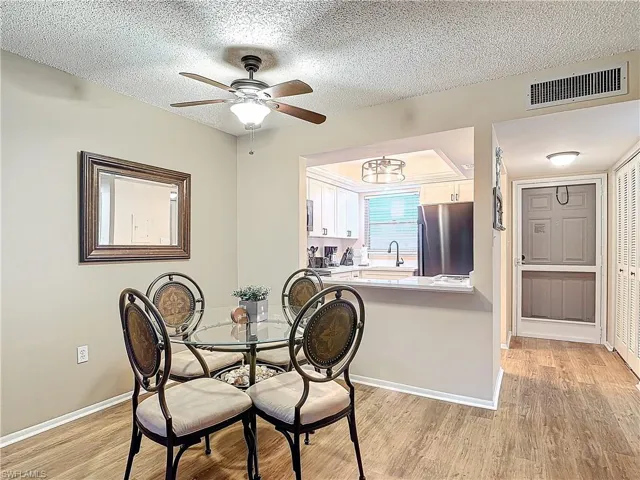 Dining room featuring sink, light wood-type flooring, ceiling fan, and a textured ceiling