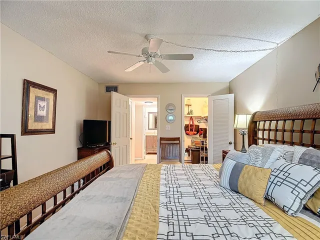 Bedroom with a closet, a spacious closet, a textured ceiling, and ceiling fan