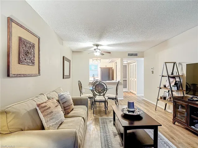 Living room featuring light hardwood / wood-style flooring, a textured ceiling, and ceiling fan