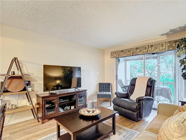 Living room with a textured ceiling and light hardwood / wood-style flooring