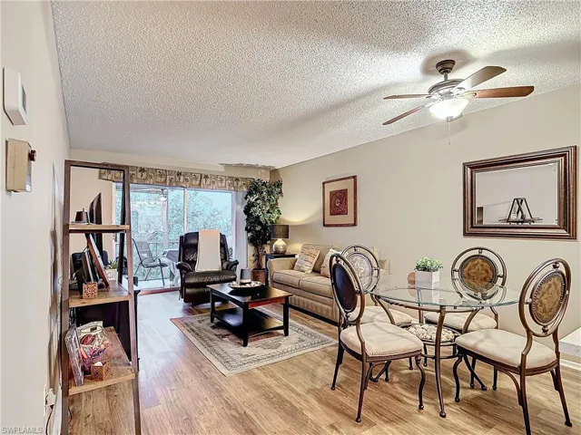 Living room with a textured ceiling, wood-type flooring, and ceiling fan