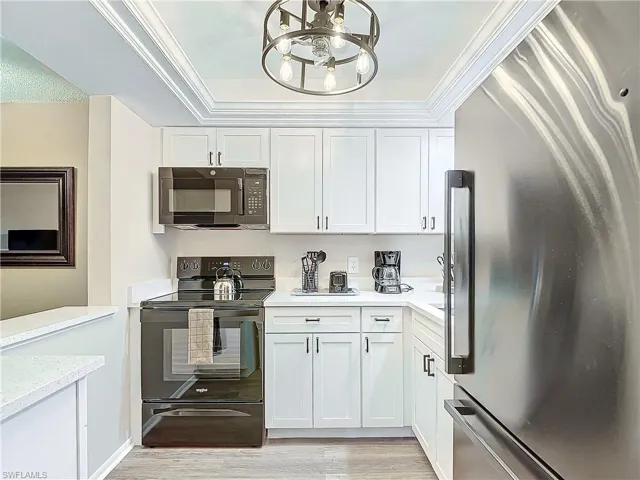 Kitchen featuring white cabinetry, black appliances, light wood-type flooring, and ornamental molding