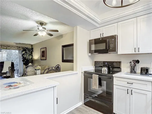 Kitchen featuring light hardwood / wood-style flooring, black appliances, a textured ceiling, white cabinetry, and ceiling fan