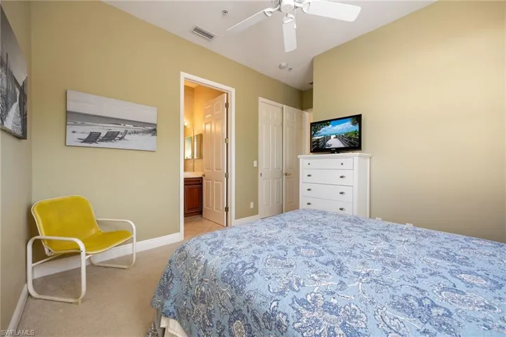 Bedroom with light carpet, a ceiling fan, and ensuite bathroom