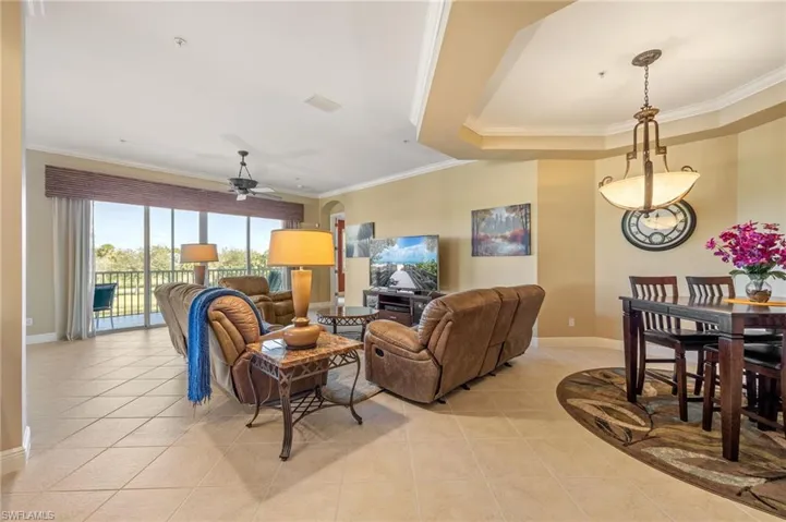Living area with ornamental molding, ceiling fan, and light tile patterned flooring