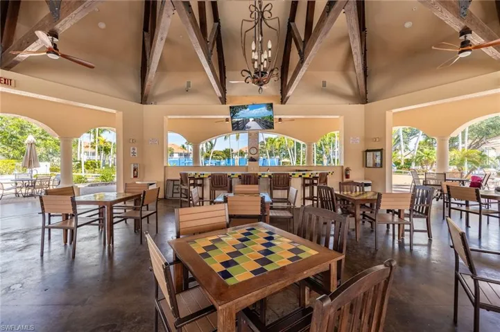 Dining room with ceiling fan, concrete flooring, a chandelier, lofted ceiling, and decorative columns