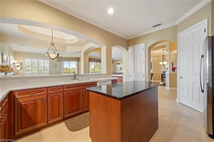 Kitchen featuring crown molding, hanging light fixtures, plenty of natural light, light tile patterned floors, and freestanding refrigerator