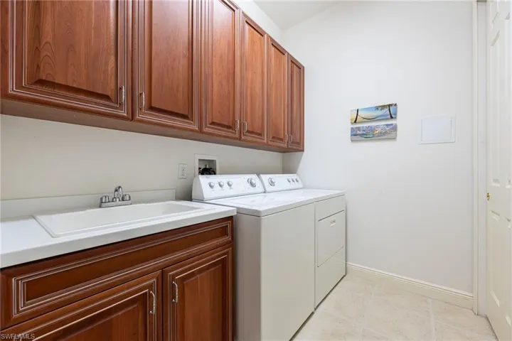 Laundry room featuring cabinet space, washer and dryer, and light tile patterned flooring