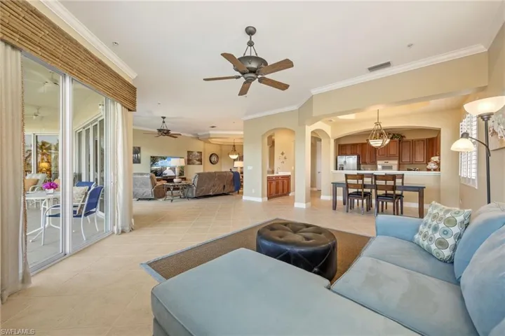 Living room with arched walkways, ornamental molding, and light tile patterned floors