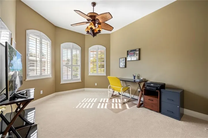 Office with light carpet and a ceiling fan