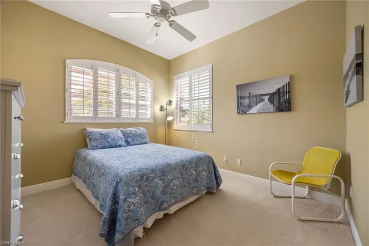 Carpeted bedroom with ceiling fan and baseboards