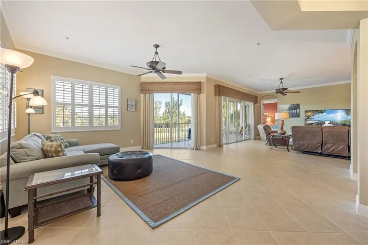 Living room with ceiling fan, light tile patterned floors, and ornamental molding