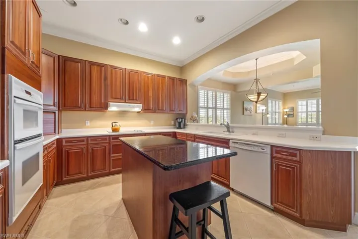 Kitchen with a breakfast bar, white appliances, pendant lighting, ornamental molding, and light tile patterned flooring
