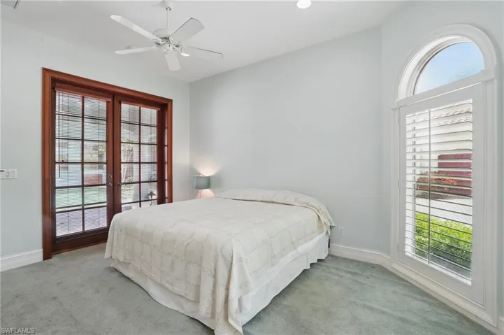 Serene bedroom with multiple windows, french doors, and recessed lighting