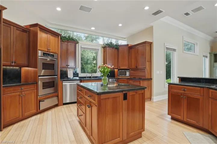 Kitchen featuring appliances with stainless steel finishes, light wood-style floors, and ornamental molding