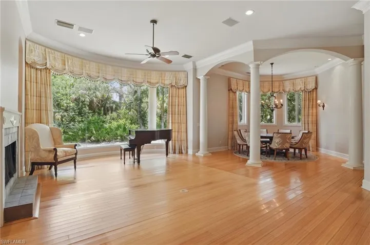 Sitting room featuring ornate columns, ceiling fan, ornamental molding, plenty of natural light, and arched walkways