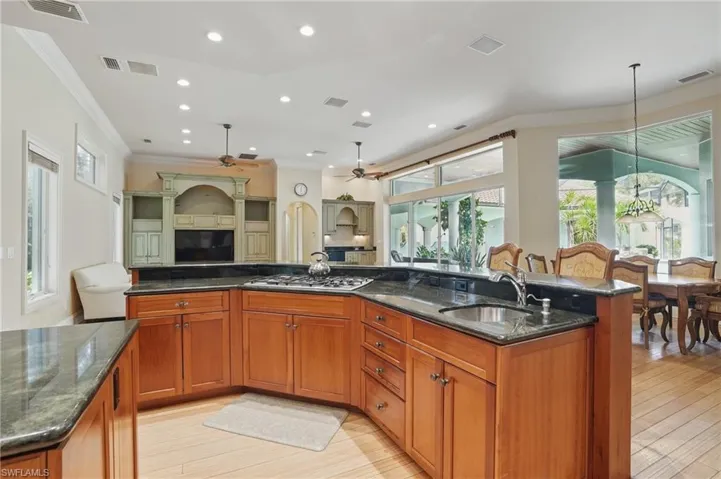 Kitchen featuring open floor plan, stainless steel gas cooktop, sink, crown molding, and a ceiling fan