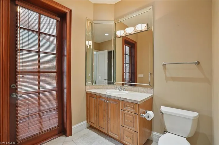 Bathroom with toilet, vanity, baseboards, and tile patterned flooring