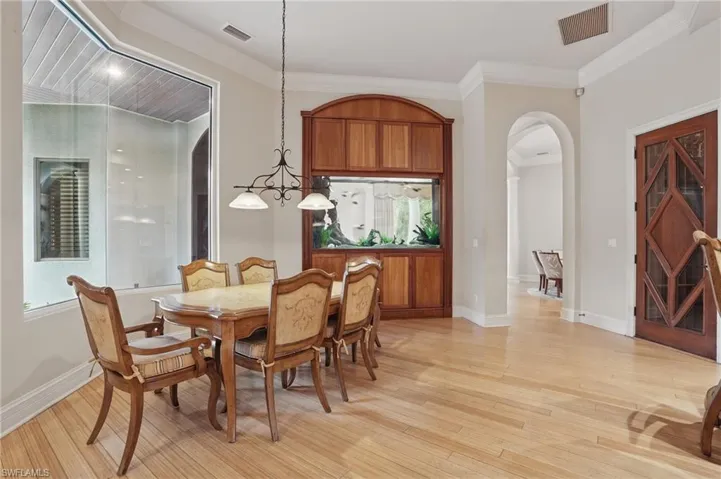 Dining space featuring arched walkways, light wood-style floors, crown molding, and baseboards