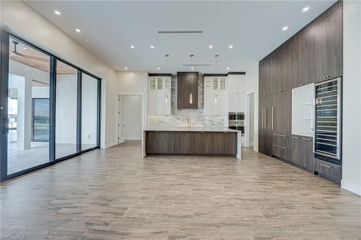Kitchen with two tone cabinets, open floor plan, a spacious island, wine cooler, and modern cabinets