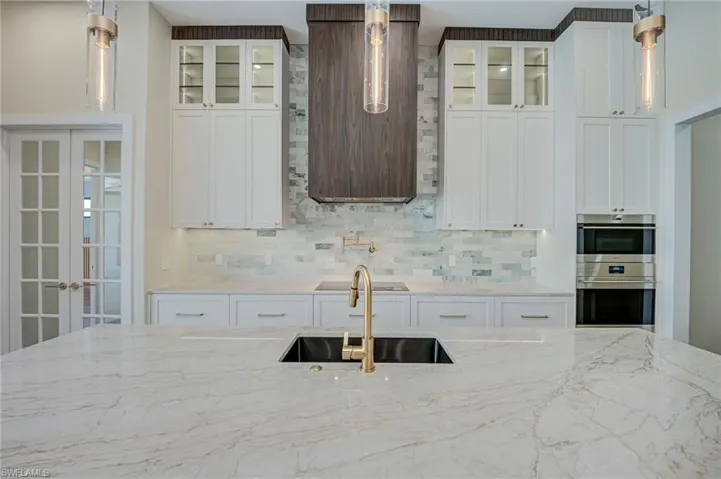 Kitchen featuring pendant lighting, white cabinetry, and glass fronted cabinets