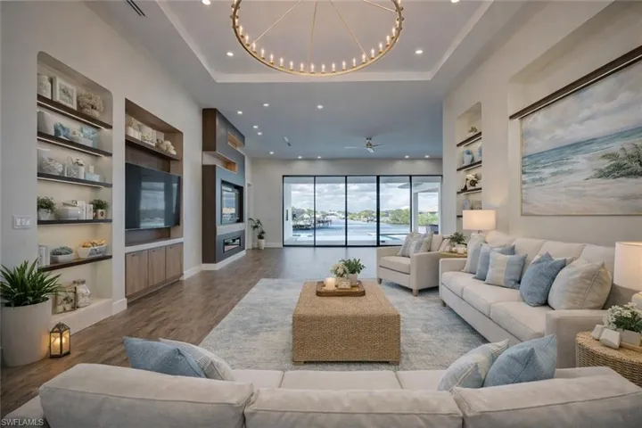 Living area with built in shelves, wood finished floors, recessed lighting, and a ceiling fan