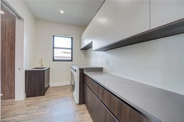 Laundry area with light wood-style floors, cabinet space, and recessed lighting