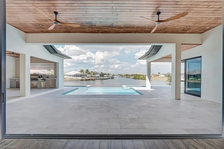 Outdoor pool with exterior kitchen, a patio area, and a residential view