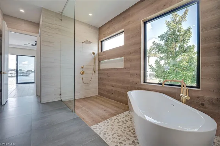 Bathroom with walk in shower, a soaking tub, and light tile patterned flooring