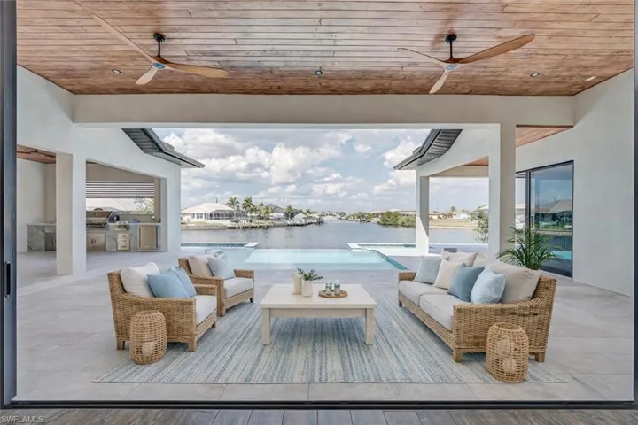 View of patio featuring ceiling fan, an outdoor kitchen with living area, and a water view